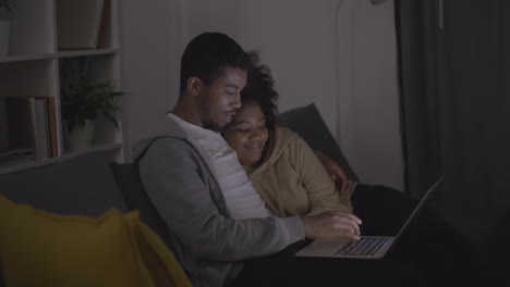 young couple picking a programme or film to watch on the laptop