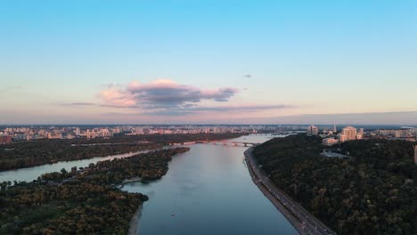 aerial ascending shot of the city of kiev with the dnipro river during the sunset