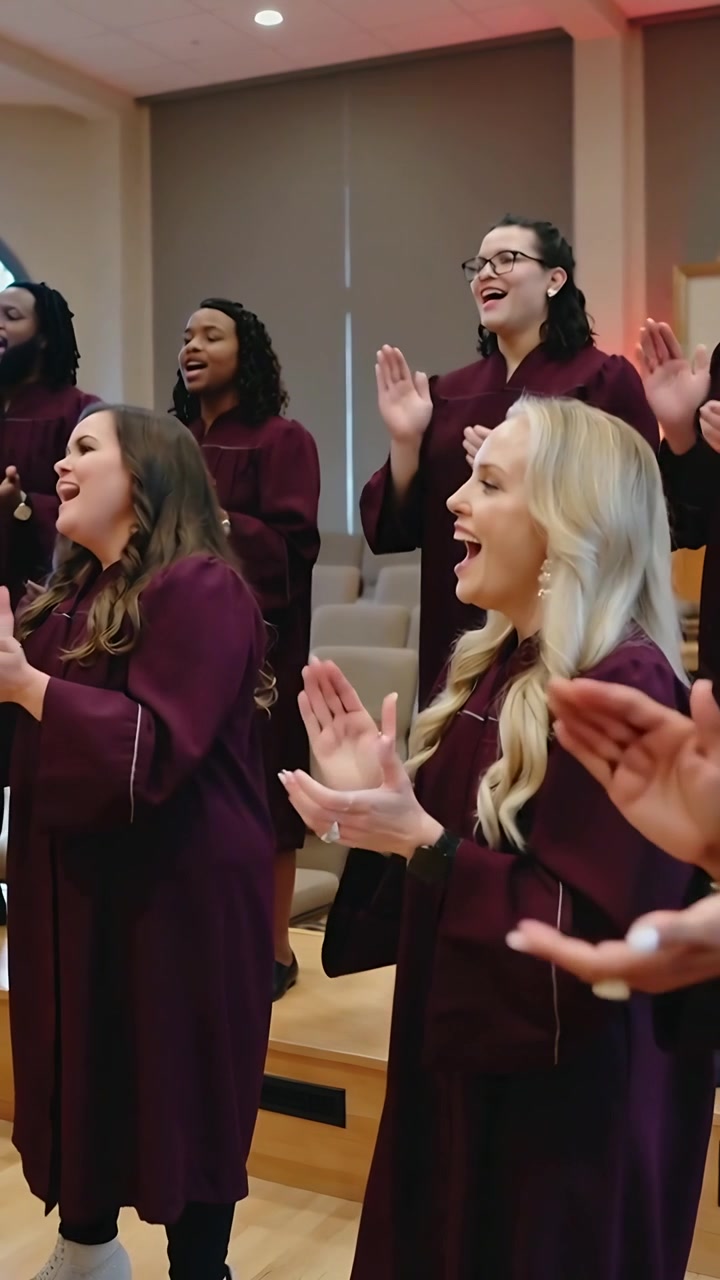 Vertical video: Reacting to conductor cue, choir clapping and singing on risers, maroon robes