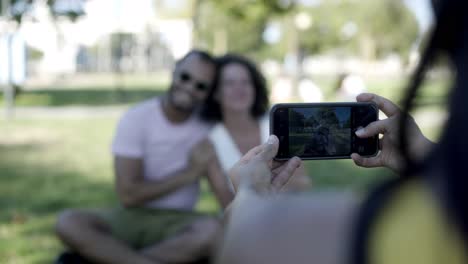 woman photographing friends with smartphone