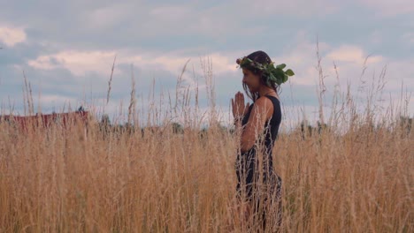 gorgeous woman praying in the midst of golden crops in olomouc, czech republic on a sunset - tracking shot - slow motion