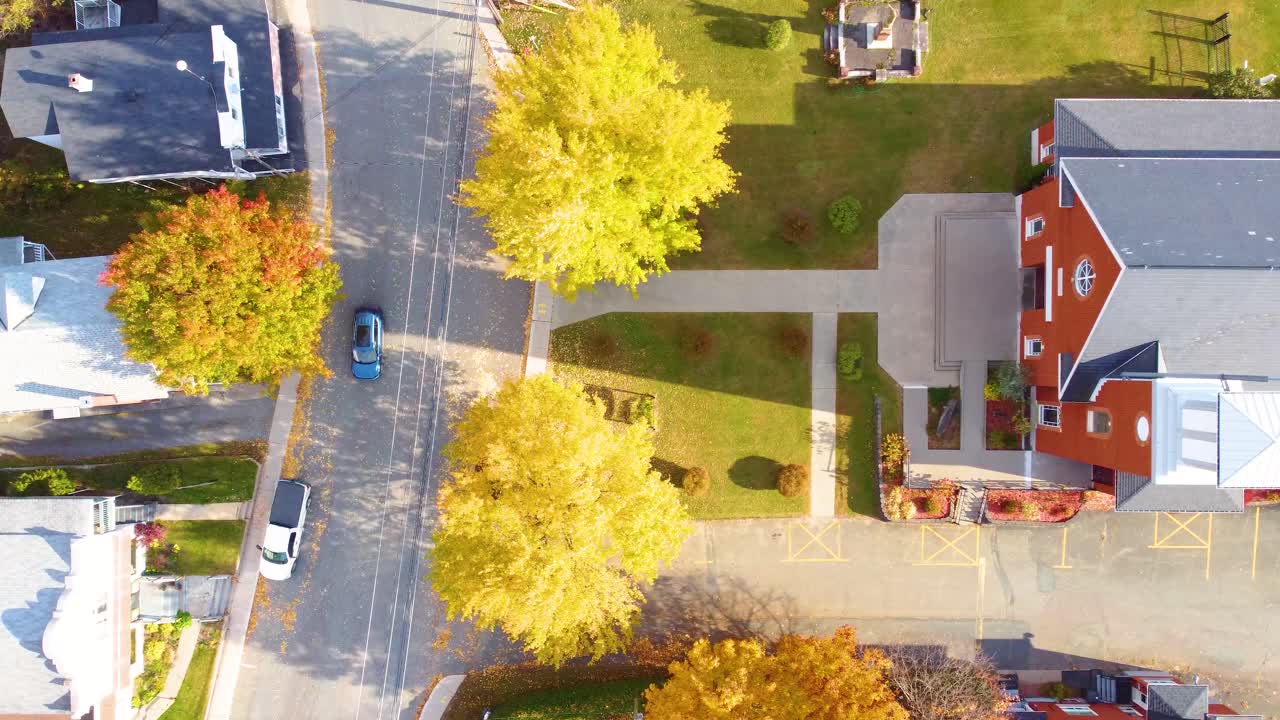 Generic suburban town with bright trees and church parking lot in fall, warm hues of autumn foliage