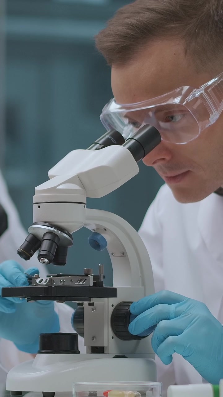 Male Scientist Examining Samples with a Microscope in a Laboratory