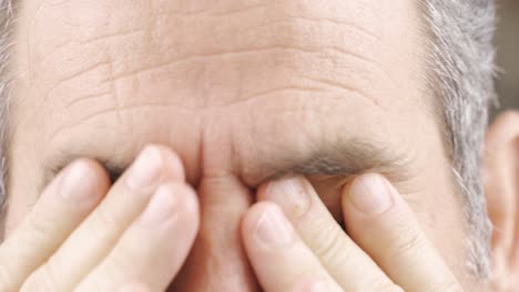 mature man with tired eyes taking off his glasses.