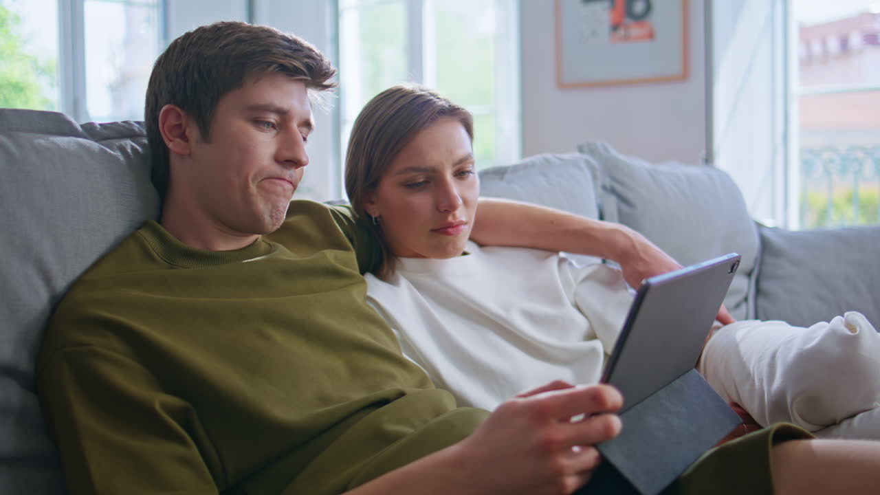 Young pair staring pad digital device at home closeup. Relaxed teenagers weekend