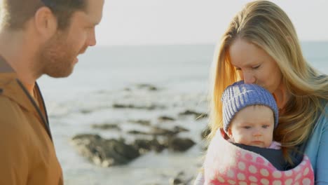 mid adult caucasian parents kissing baby at beach on a sunny day 4k