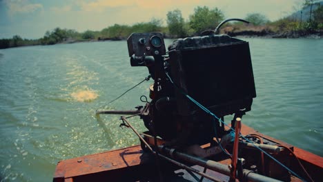 engine of a long-tail boat sailing down a river in thailand