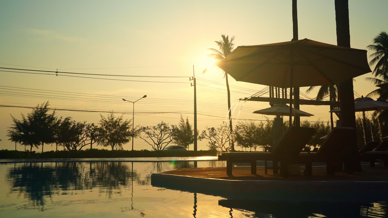 바다를 배경으로 수영장 주변에 침대 수영장이 있는 우산 - 휴일 및 휴가 개념