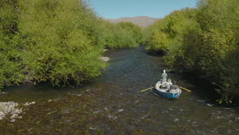 Gorgeous-aerial-tracking-shot-following-a-small-fishing-boat-floating-down-river-in-Argentina