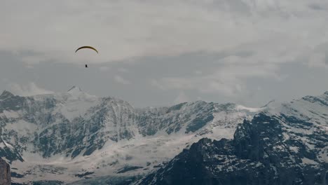 Gleitschirmflieger-In-Richtung-Schneebedeckter-Alpen-In-Der-Schweiz