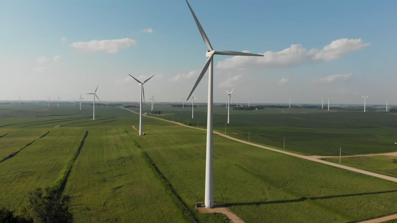 Aerial video of flying up and around a wind generator in a cornfield on a sunny day in Iowa