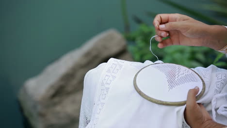lady hands doing cross stitching. close up of process of working on a piece of embroidery