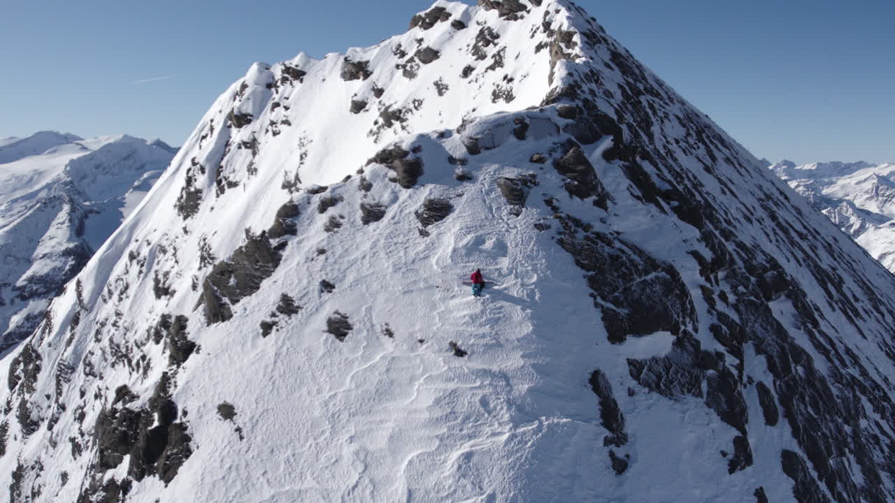 오스트리아의 키츠슈타인호른 산의 가파른 눈  ⁇ 인 벽에 산악 등반자의 화려한 드론  ⁇  - 정상에 십자가의 실루 ⁇  - 뒤로 비행
