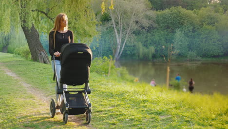 Joven-Madre-Caucásica-Caminando-En-El-Parque-Con-Un-Cochecito