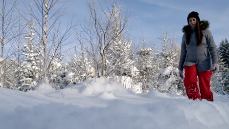 Close-up-shot-of-a-woman-in-black-warm-winter-coat-and-red-pant,-walking-through-thick-layer-of-white-snow-on-a-cold-winter-morning