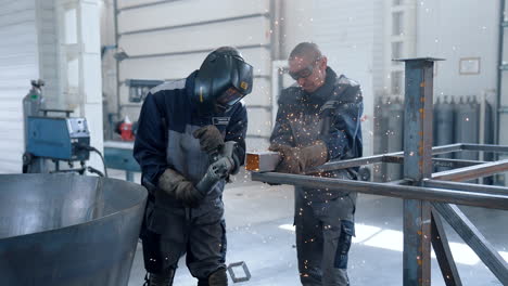 vinnytsia, ukraine - january 19, 2023: heavy industry engineering factory interior with workers using angle grinder and cutting metal