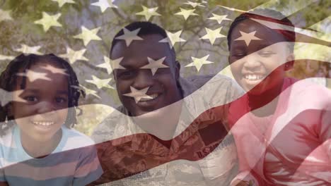 animation of flag of america over happy african american soldier father embracing son and daughter