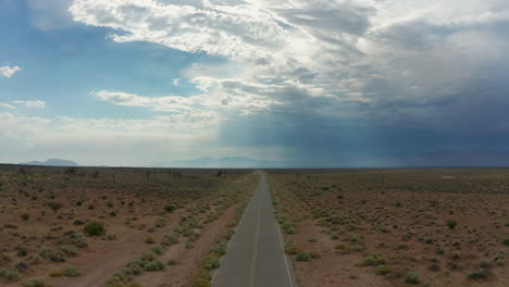Aerial-descent-over-an-empty-road-stretching-out-into-the-barren-Mojave-Desert