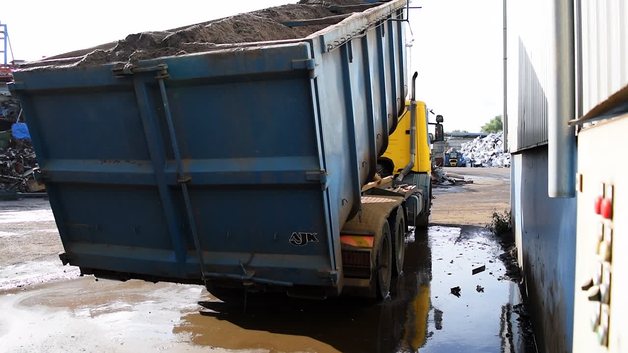 A truck lifts of the ground while loading an overweight container filled with dust,