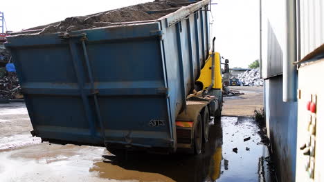 a truck lifts of the ground while loading an overweight container filled with dust,