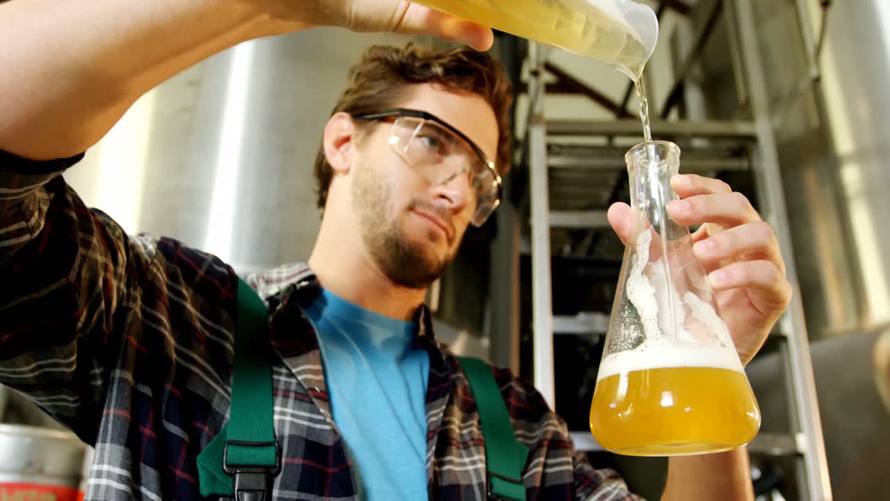 cervecero vertiendo cerveza en un matraz de laboratorio 4k