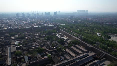 aerial view of pingyao, historic walled old town with modern tall buildings in the hazy background
