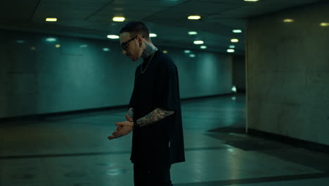 stylish man with tattoos in subway tunnel