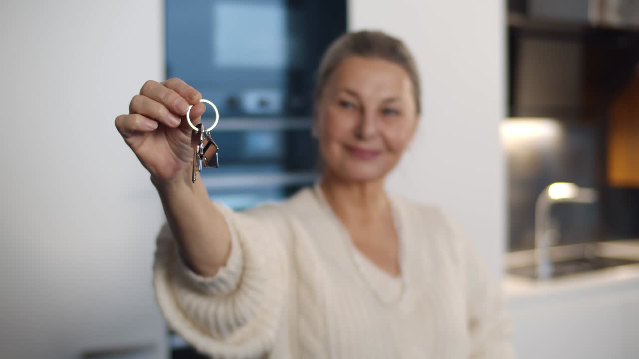 retrato de una mujer mayor sonriente mostrando las llaves de una casa nueva en la cámara