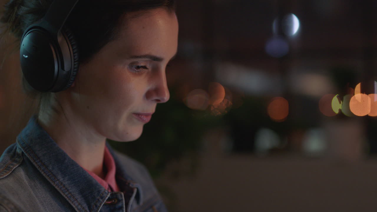 close up caucasian business woman working late using laptop computer typing project manager browsing online research planning deadline listening to music in office at night