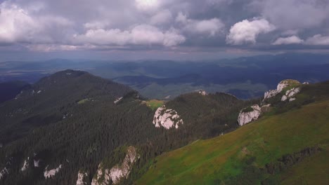 An-aerial-drone-shot-moving-backward-revealing-a-green-mountain-landscape