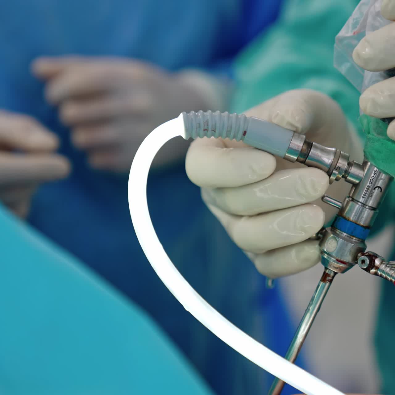 Medical device used for laparoscopic surgeries. Hands of doctor in latex gloves holding the tool input into patient's body through a tiny incision. Close up