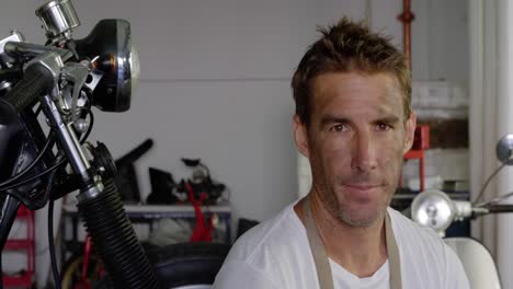 mecánico masculino bebiendo café en el garaje de reparación de motocicletas 4k