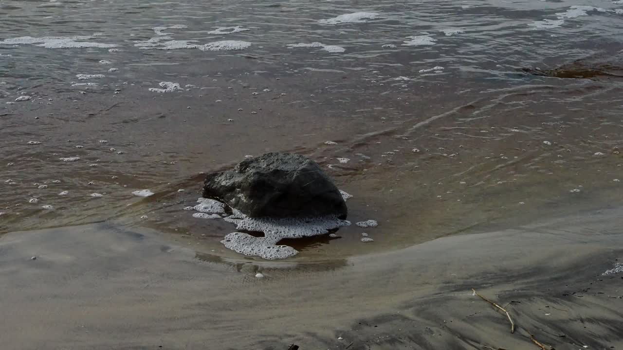 Water moving around a rock in the sand