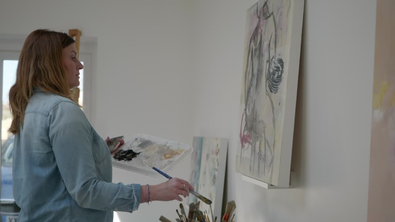 figura de pintura de artista femenina en un lienzo, de pie en un estudio casero