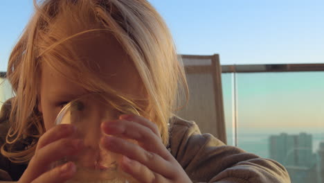 child having juice for breakfast on the balcony