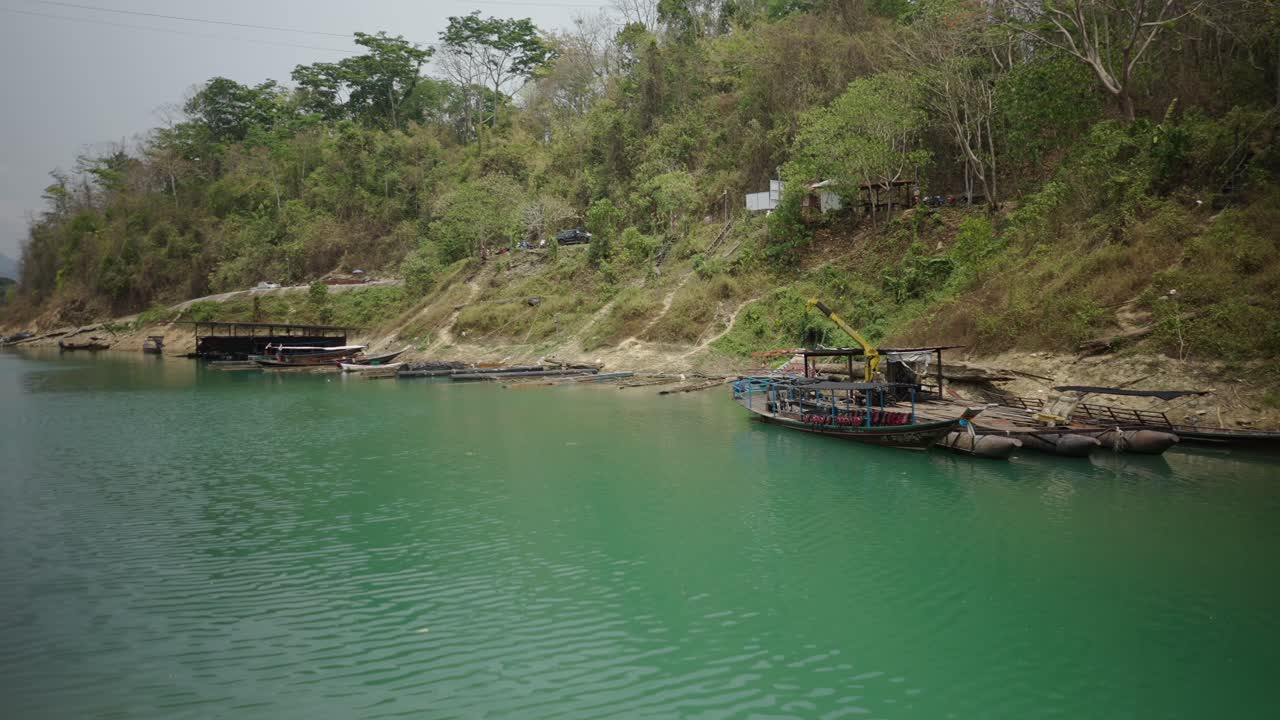 Boats Docked on a Green Riverbank with Hilly Landscape