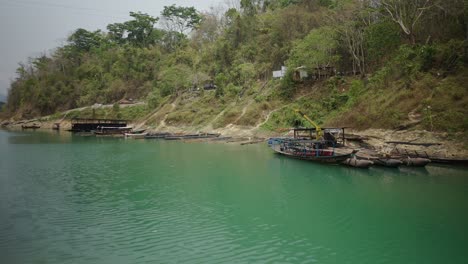 boats docked on a green riverbank with hilly landscape