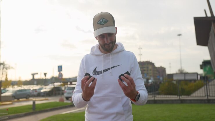 Man with beard and cap evaluating differences between DJI Osmo Action 4 and GoPro 12 cameras for technical comparison