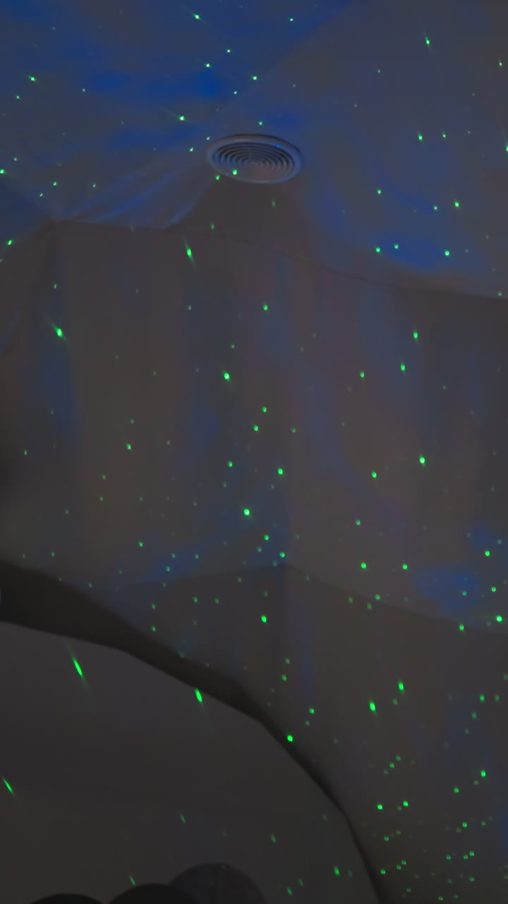 Double bed in glamping house with green lights on ceiling. Nightlight with projector that lights up room with green dots for quiet sleep