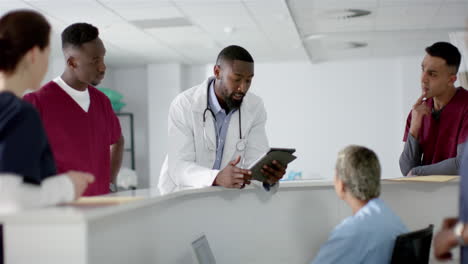 Verschiedene-Ärzte-Besprechen-Ihre-Arbeit,-Benutzen-Ein-Tablet-An-Der-Rezeption-Im-Krankenhaus,-Zeitlupe