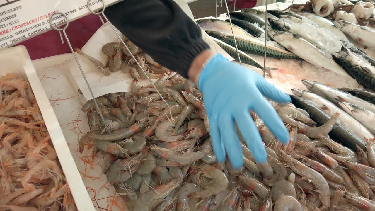 세일즈맨은 새우를 가져다가 종이 시트에 올려 놓고 시장에서 생선을 소매합니다.