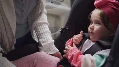 Mid-section-of-caucasian-mother-keeping-her-baby-in-safety-seat-in-the-car