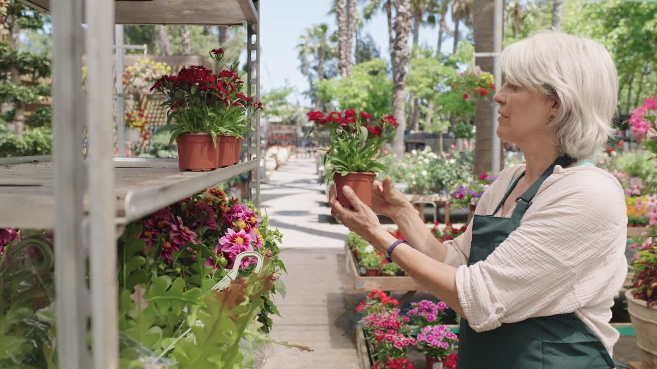 A woman tending to flowers at a garden center