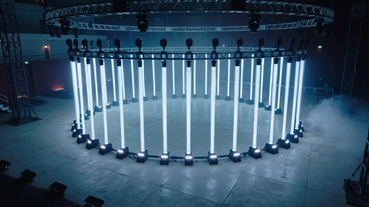 Pulling back camera revealing circular LED ring in production hall, exposing full setup with haze