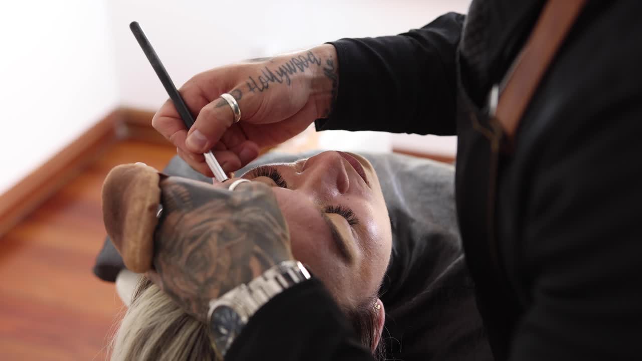 Male makeup artist working with female model