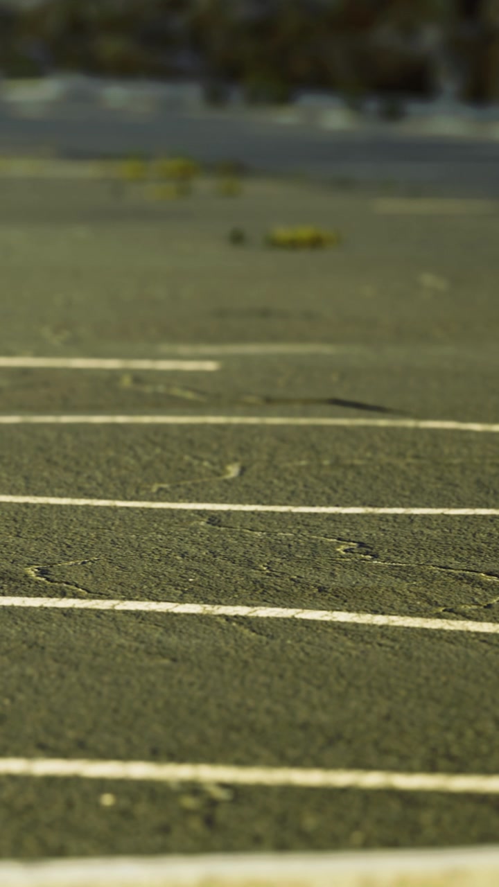 Empty parking lot under a blue sky beside a quiet road