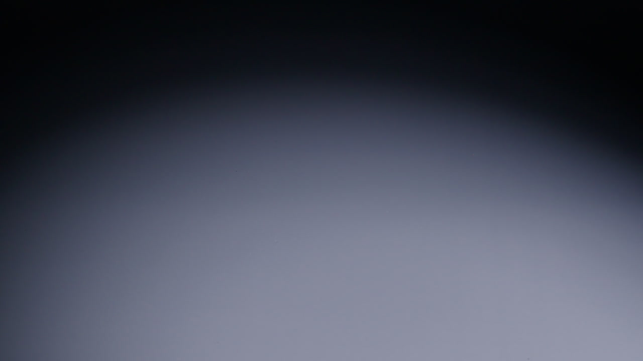 Slow motion wide shot of blue role-playing game die as it rolls across the screen from right to left and out of shot