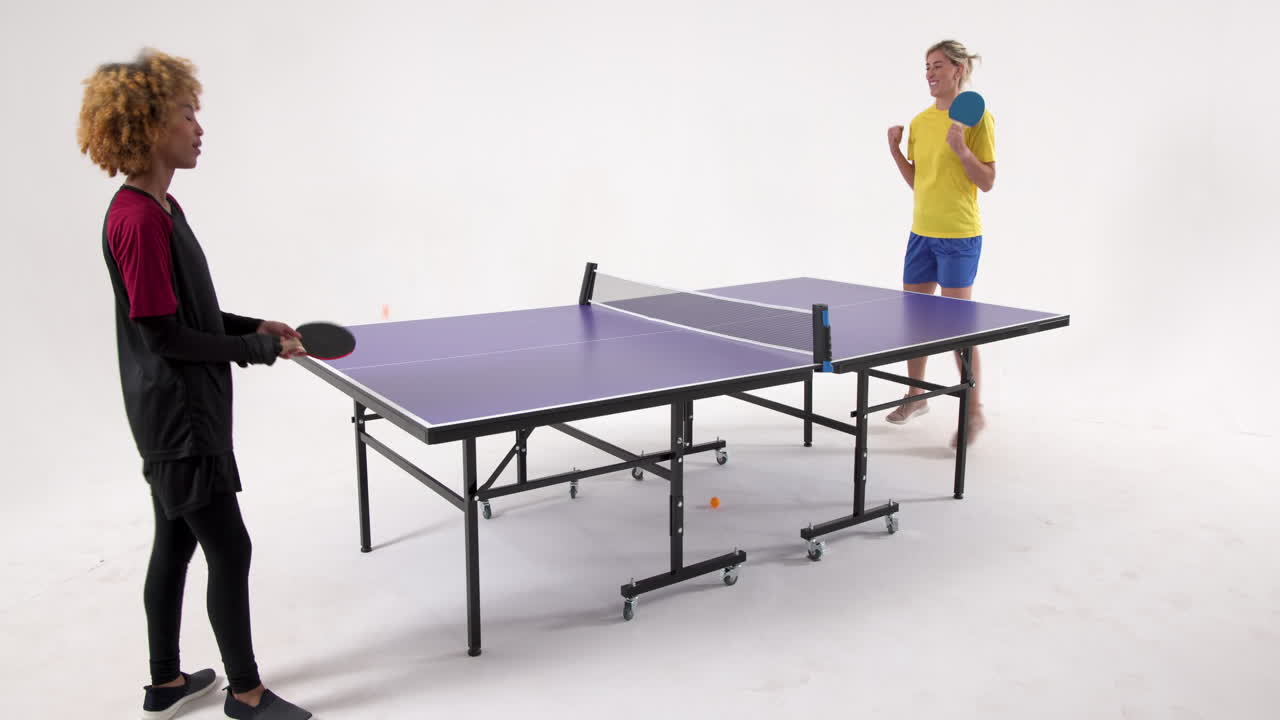 Multiracial female table tennis players, passing the ball, shaking hands on white background