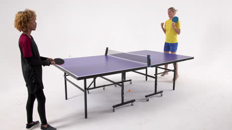 multiracial female table tennis players, passing the ball, shaking hands on white background