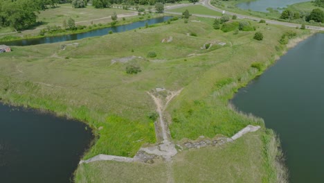 Aerial-establishing-view-of-abandoned-historical-concrete-seaside-fortification-buildings,-Southern-Forts-near-the-beach-of-Baltic-sea-in-Liepaja,-sunny-summer-day,-drone-shot-moving-backward,-tilt-up